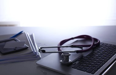 Dizüstü bilgisayarı, steteskopu ve defteri olan bir doktorun çalışma yeri.
