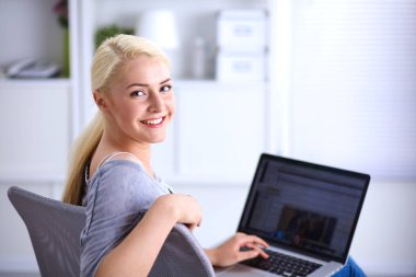 Genç ve güzel bir kadın evde dizüstü bilgisayar kullanıyor.