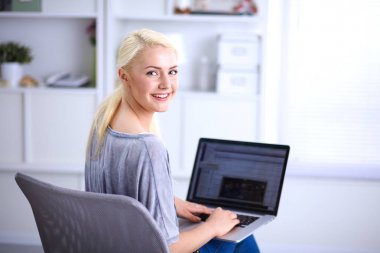 Genç ve güzel bir kadın evde dizüstü bilgisayar kullanıyor.