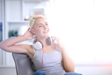 Evdeki genç ve güzel kadın kanepede oturup müzik dinliyor.