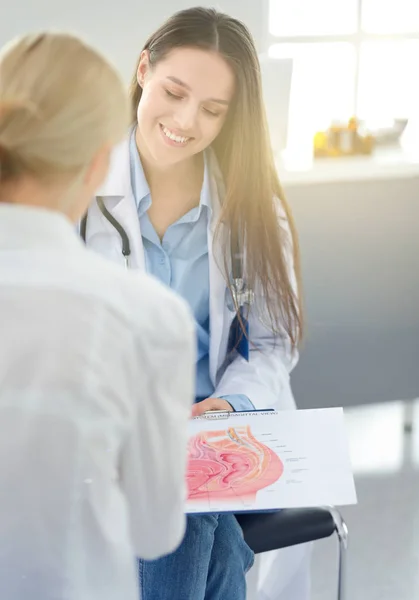 Doktor ve hasta masada otururken bir şey tartışıyorlar. İlaç ve sağlık hizmetleri kavramı — Stok fotoğraf