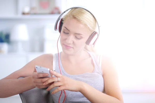 Jonge mooie vrouw thuis zitten op de bank en luisteren muziek — Stockfoto