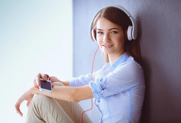 Gelukkig meisje zittend op de vloer en muziek luisteren — Stockfoto