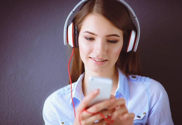 Gelukkig meisje zittend op de vloer en muziek luisteren — Stockfoto