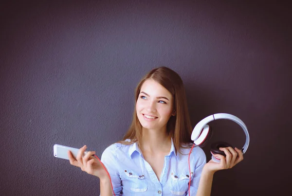 Young happy girl sitting on floor and listening music — Stock Photo, Image