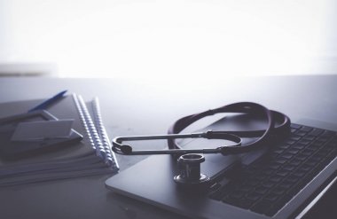 Dizüstü bilgisayarı, steteskopu ve defteri olan bir doktorun çalışma yeri.