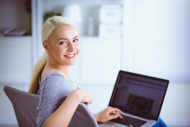 Genç ve güzel bir kadın evde dizüstü bilgisayar kullanıyor.