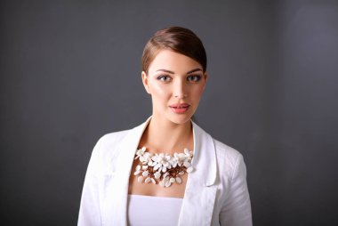 Boncuklar, gri arka plan üzerinde duran genç kadın portresi