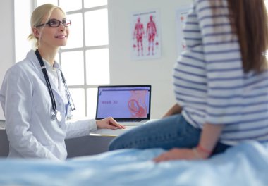 Hastanede doktorla gülümseyen güzel bir hamile kadın.