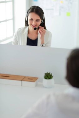 Ofisinde kulaklık ve bilgisayarla gülümseyen iş kadını ya da yardım hattı operatörü