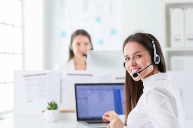 Smiling businesswoman or helpline operator with headset and computer at office clipart