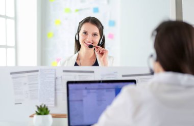 Ofisinde kulaklık ve bilgisayarla gülümseyen iş kadını ya da yardım hattı operatörü