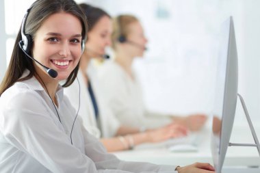 Ofisinde kulaklık ve bilgisayarla gülümseyen iş kadını ya da yardım hattı operatörü