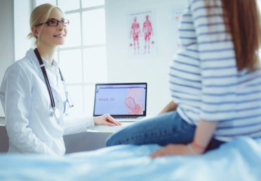 Hastanede doktorla gülümseyen güzel bir hamile kadın.