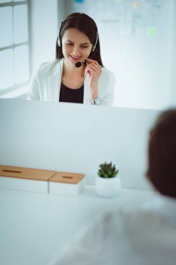 Ofisinde kulaklık ve bilgisayarla gülümseyen iş kadını ya da yardım hattı operatörü