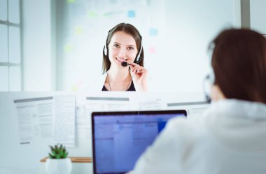 Ofisinde kulaklık ve bilgisayarla gülümseyen iş kadını ya da yardım hattı operatörü