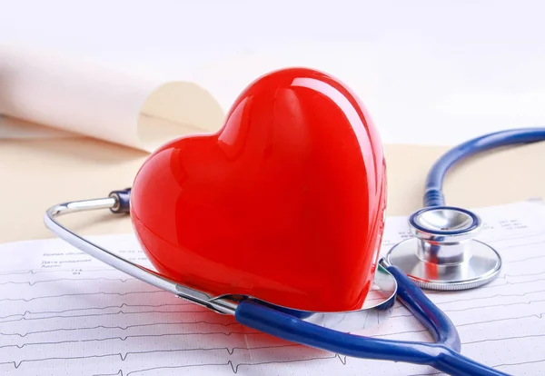 Red heart and a medical stethoscope at desk — Stock Photo, Image