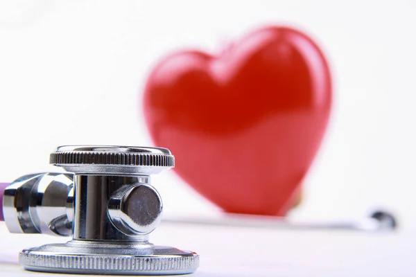 Red heart and a medical stethoscope at desk — Stock Photo, Image