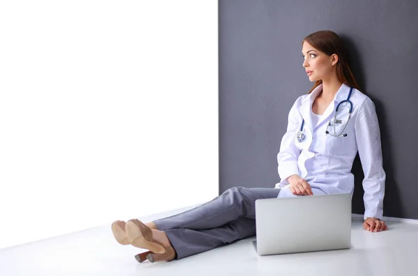 Mujer joven médico sentado en el piso del hospital con el ordenador portátil — Foto de Stock