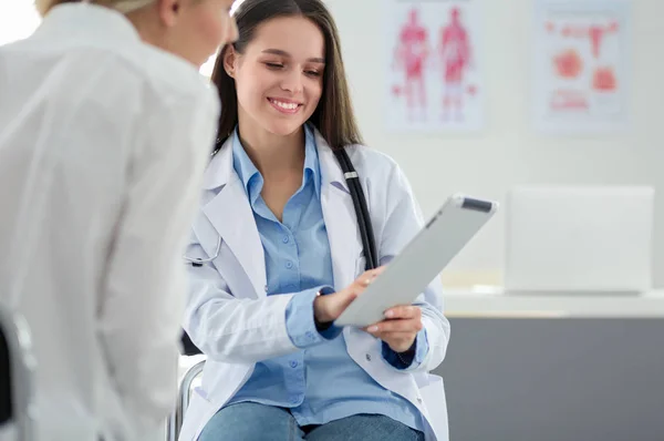 Doktorn och patienten diskuterar något när de sitter vid bordet. Medicin och hälsovård — Stockfoto