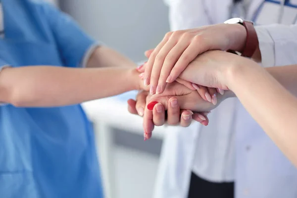 Médicos y enfermeras en un equipo médico apilándose las manos — Foto de Stock