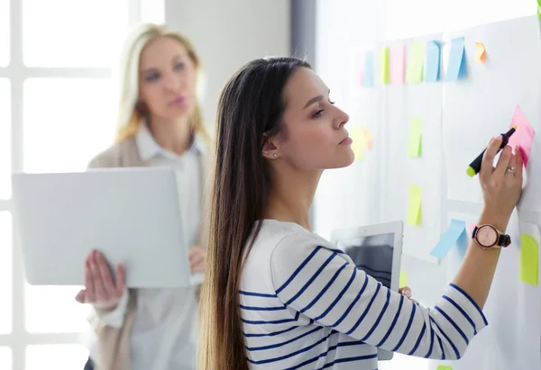 Closeup on business woman writing in flipchart in office — Stock Photo, Image