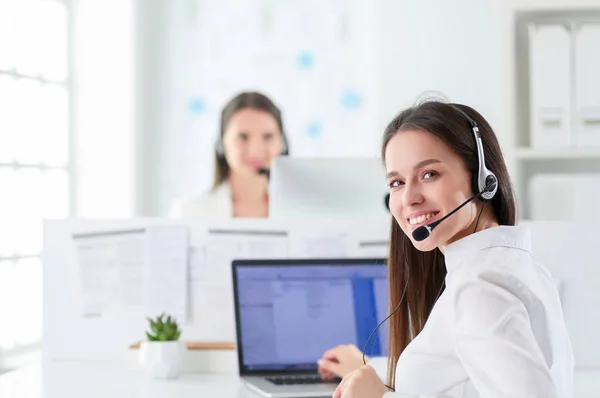 Mujer de negocios sonriente u operador de línea de ayuda con auriculares y computadora en la oficina —  Fotos de Stock