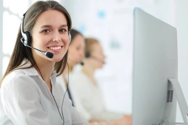 Mujer de negocios sonriente u operador de línea de ayuda con auriculares y computadora en la oficina — Foto de Stock