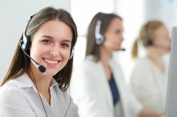 Mujer de negocios sonriente u operador de línea de ayuda con auriculares y computadora en la oficina — Foto de Stock