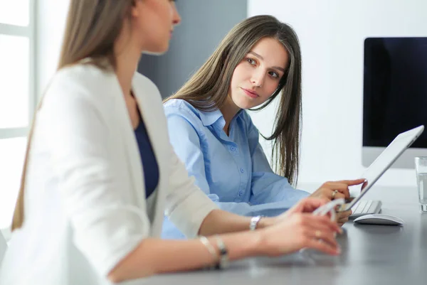 Zwei Bürokolleginnen sitzen auf dem Schreibtisch — Stockfoto