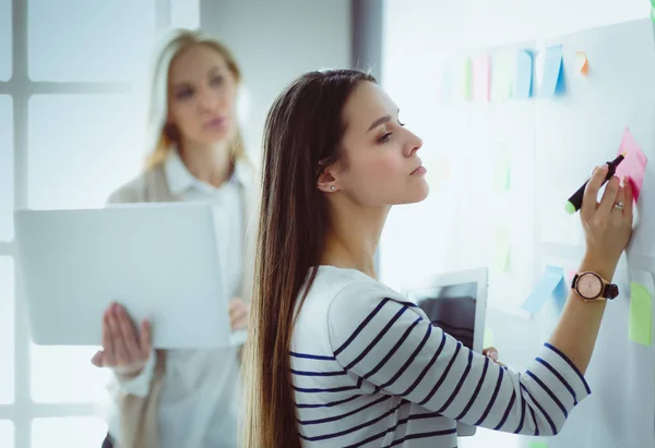 Nahaufnahme einer Geschäftsfrau, die im Büro im Flipchart schreibt — Stockfoto