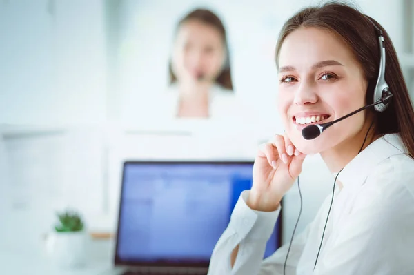 Ofisinde kulaklık ve bilgisayarla gülümseyen iş kadını ya da yardım hattı operatörü — Stok fotoğraf
