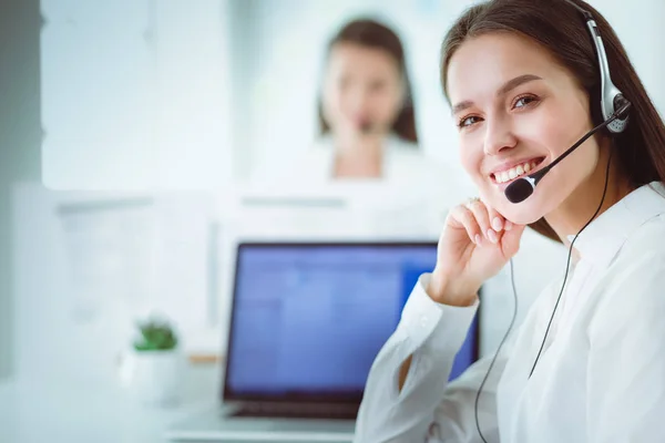 Mujer de negocios sonriente u operador de línea de ayuda con auriculares y computadora en la oficina — Foto de Stock