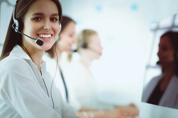 Mujer de negocios sonriente u operador de línea de ayuda con auriculares y computadora en la oficina —  Fotos de Stock