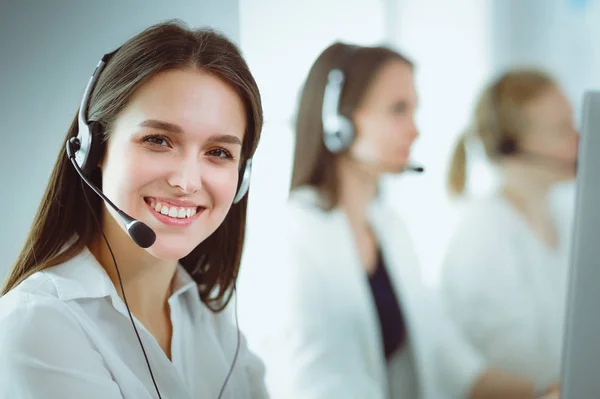 Mujer de negocios sonriente u operador de línea de ayuda con auriculares y computadora en la oficina — Foto de Stock