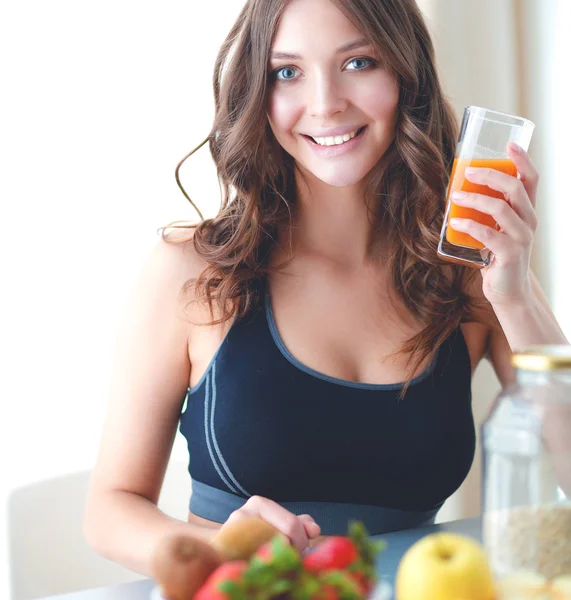 女孩坐在厨房的桌子上的水果和果汁的眼镜 — 图库照片