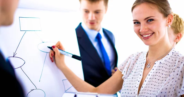 Businesswoman writing on flipchart while giving presentation to colleagues in office — Stock Photo, Image