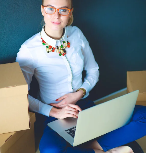 Femme assise sur le sol près d'une boîte avec ordinateur portable — Photo