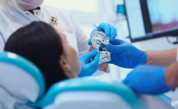 Senior male dentist in dental office talking with female patient and preparing for treatment