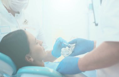 Diş kliniğinde duran gülümseyen bir dişçinin portresi.