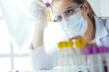 Hastanedeki kan örneğini analiz eden güzel bir kadın laboratuvar asistanı portresi.