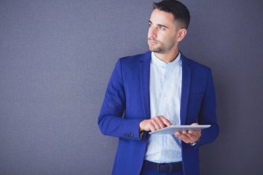 Gri arka planda yalnız oturan genç iş adamı.