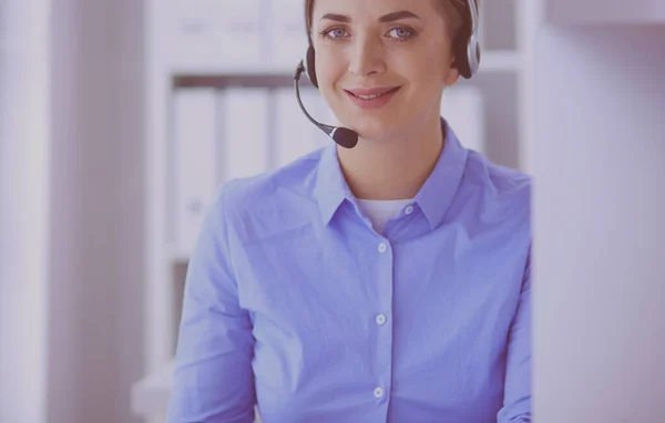 Ernstige mooie jonge vrouw die werkt als support telefoon operator met headset in het kantoor — Stockfoto