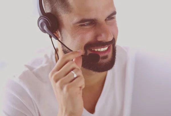 Retrato de un joven con un auricular frente a una computadora portátil — Foto de Stock