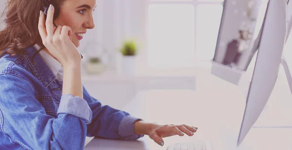 Felice affascinante giovane donna seduta e lavorare con il computer portatile utilizzando cuffie in ufficio — Foto Stock