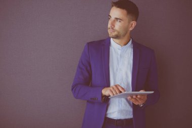 Gri arka planda yalnız oturan genç iş adamı.