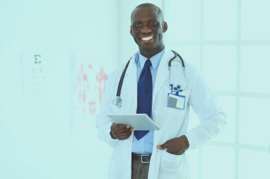 Tablet bilgisayarlı siyahi bir doktor hastanede bekliyor.
