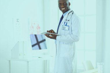Tablet bilgisayarlı siyahi bir doktor hastanede bekliyor.