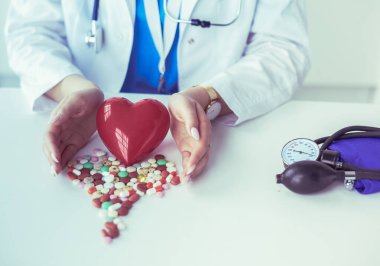 Masada kırmızı kalbi ve steteskopu olan kardiyolog.