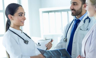 Bayan bir doktor başka bir doktora ofisinde röntgen gösteriyor.